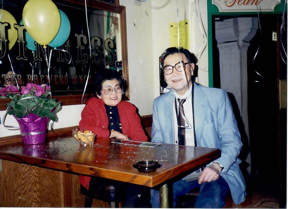 Two people sitting at a table with balloons around them