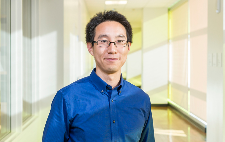 A photo of a man in a blue shirt standing in a hallway.