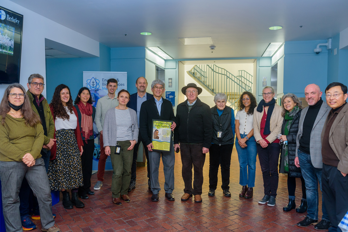 A group PMB and Rausser College students, faculty, and staff pose for a photo in the center of the Koshland Hall lobby.