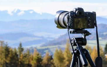 A camera on a tripod facing a mountain range 