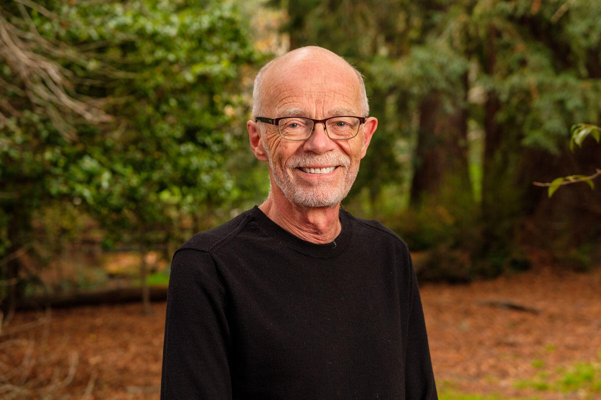 Headshot portrait of PMB professor John Taylor with forest/woodland backdrop